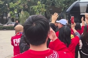 球迷?shī)A道歡迎重慶銅梁龍球隊(duì)大巴，并高舉雙手喊“重慶雄起！”